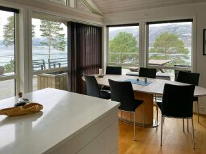 a kitchen with a table and chairs and windows at Seaside Cabin With Private Pier In Eidsvåg in Eidsvåg