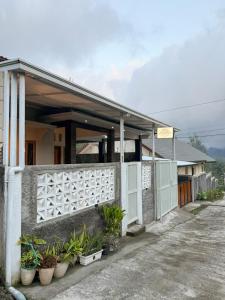 a house with a white fence and potted plants at Tafufu Villa Tumpak Sewu in Sumberbopong