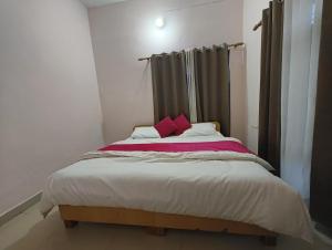 a bed with two pink pillows in a room at Hotel Shubh Yatra in Nandaprayāg