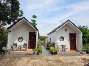 a white building with two doors and some chairs at Bunrapee House in Nan