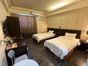 ein Hotelzimmer mit zwei Betten und einem Fernseher in der Unterkunft Dreamer Hotel in Budai + 17 Fotos