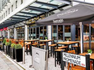 a restaurant with tables and umbrellas on a street at ibis Bristol Centre in Bristol