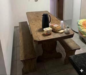 a wooden table with a tea kettle and bread on it at Hotel Airton in Ivaiporã