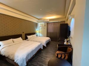 ein Hotelzimmer mit zwei Betten und einem Fernseher in der Unterkunft Dreamer Hotel in Budai