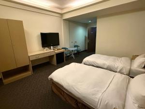 ein Hotelzimmer mit zwei Betten und einem Fernseher in der Unterkunft Dreamer Hotel in Budai