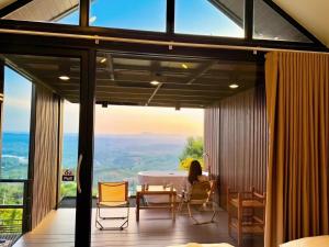 a woman sitting in a room with a table and chairs at Heaven Khaokho2 in Khao Kho