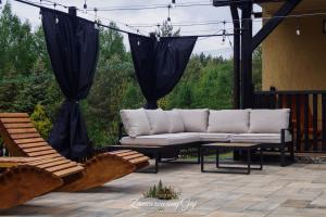 a couch on a patio with two chairs and a table at Zaczarowany Gaj in Gaj Grzmięca