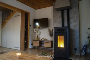 a living room with a fireplace and a tv on the wall at Zaczarowany Gaj in Gaj Grzmięca