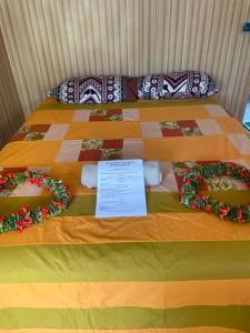 a bed with flowers on it with a sign on it at PENSION NATIRENA LODGE Hao in Otepa