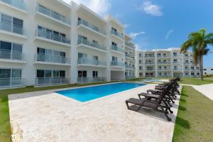 a large apartment building with a swimming pool and chairs at Aura Sosua Ocean Village in Sosúa