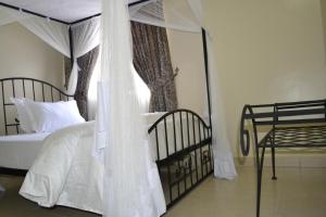 a bedroom with a canopy bed and a window at Zakinn Hotel Gangilonga in Iringa