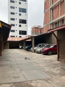 a parking lot with cars parked next to tall buildings at Imperio Carlos V in Oruro