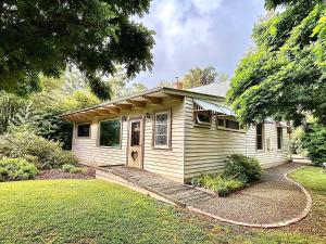 a small house with a wooden porch and a yard at Riverwood Cottage, accessible accommodation in Warburton