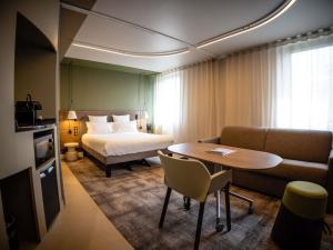 a hotel room with a bed and a table and a couch at Novotel Suites Rouen Normandie in Rouen