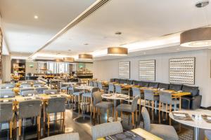 a restaurant with tables and chairs in a room at Hala Arjaan by Rotana, Deluxe Hotel Apartments in Abu Dhabi