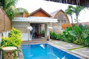 a villa with a swimming pool in front of a house at Winners surfing bali resort in Airsatang