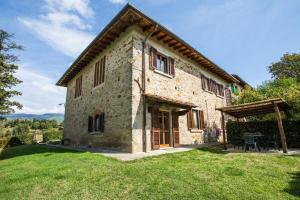 a large stone house with a grassy yard at Universal Harmony Agriturismo in Dicomano