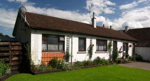 een wit huis met een bruin dak bij Hillview Cottage in Stirling