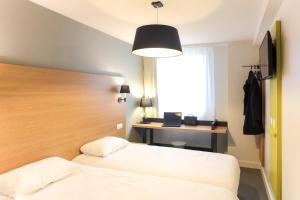 a hotel room with two beds and a desk at Hotel Reseda in Bagnolet