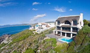 an image of a house on a hill next to the ocean at Whale Huys Luxury Oceanfront Eco Villa in Gansbaai