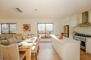 a kitchen and living room with a wooden table and a dining room at Seednest Stylish & Perfect for Relaxation in Melton South