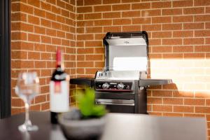 a grill with a bottle of wine next to a brick wall at Seednest Stylish & Perfect for Relaxation in Melton South