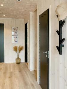 a hallway with a black door and a vase on the floor at Panoramic Cabin With Sea View On Randøy in Hjelmeland