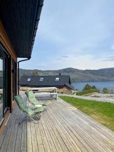 a deck with two chairs and a bench on a house at Panoramic Cabin With Sea View On Randøy in Hjelmeland