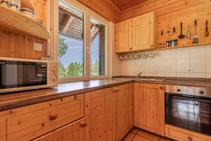 a kitchen with wooden cabinets and a microwave and a window at Kraševec Lodge with Garden & Pool - Happy Rentals in Velike Bloke