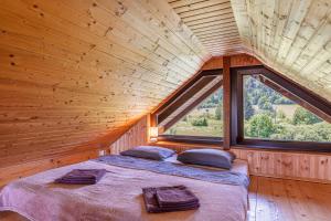 a bed in a wooden room with a large window at Kraševec Lodge with Garden & Pool - Happy Rentals in Velike Bloke +27 photos