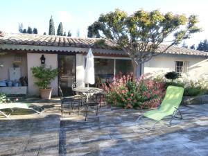 eine Terrasse mit Stühlen, einem Tisch und einem Sonnenschirm in der Unterkunft Les grands pins in Saint-Andiol