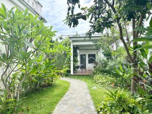 a garden path leading to a white house at Villa Rosa HueS in Thôn An Hòa