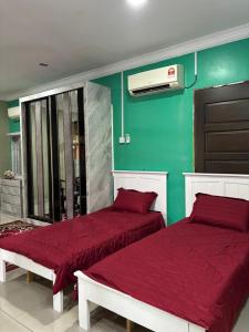 two beds with red sheets in a room with green walls at Farshada Homestay villa in Kapar +2 photos
