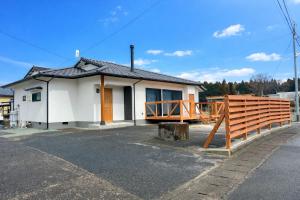 a small white house with a wooden fence at 季紀の杜阿蘇 in Aso