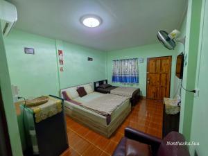 a bedroom with a bed and a couch and a window at Bunrapee House in Nan