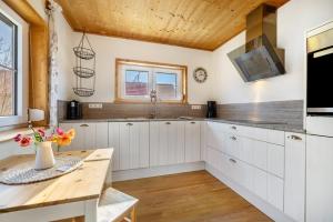 a kitchen with white cabinets and a wooden ceiling at Ferienhaus Eichenstein in Meßstetten