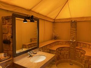 a bathroom with a sink and a large mirror at MANVĀR SEVAN, THE DESERT CAMP in Shaitrāwa