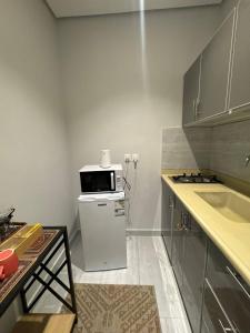 a small kitchen with a microwave on top of a refrigerator at Modren AD 23 in Dammam