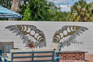 two chairs and umbrellas in front of a wall at The Ray Soulful King Studio Pool in Jacksonville