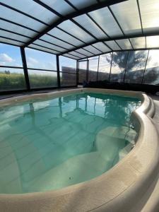 a large swimming pool in a building with windows at Le Cocooning in Asnières