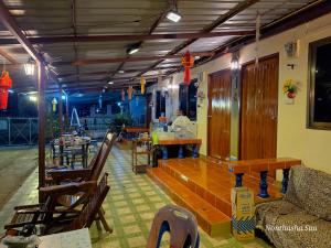 a restaurant with tables and chairs and a person in the background at Bunrapee House in Nan