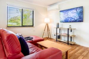 a living room with a red couch and a table at 'Flinders' in Yeppoon