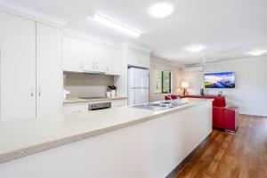 a kitchen with white cabinets and a red couch at 'Flinders' in Yeppoon +8 photos