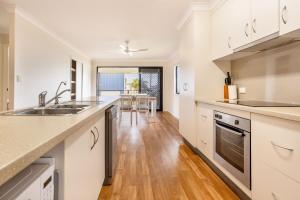 a kitchen with white cabinets and a wooden floor at 'Flinders' in Yeppoon