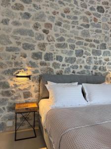 a bedroom with a stone wall with a bed and a table at Almyra Suites in Khalíkia