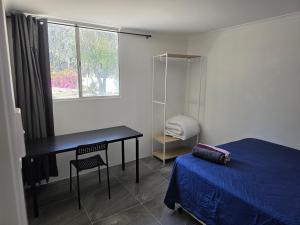 a bedroom with a bed and a desk and a window at Room in a shared farmhouse in Kelmscott