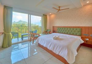 a bedroom with a large bed and a balcony at Nature Green Pool Resort Munnar by VOYE HOMES in Munnar +81 photos
