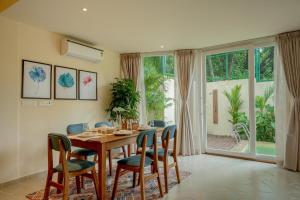 a dining room with a wooden table and chairs at SaffronStays Oslo in Anjuna