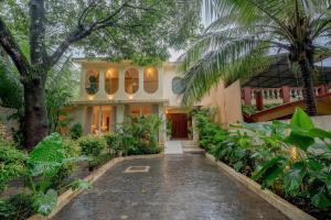 a house with a courtyard with trees and plants at SaffronStays Oslo in Anjuna