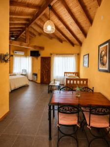 a living room with a wooden table and a bedroom at Cabañas La Matera Apart in Los Reartes
